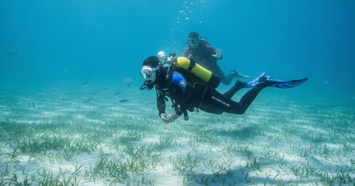 New diver swimming calmly above a sandy seabed with an instructor nearby