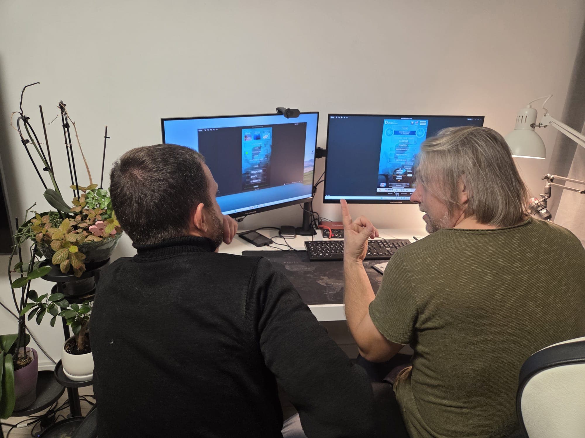 Two of the team at a desk with two monitors, reviewing an early version of Diving Scanner